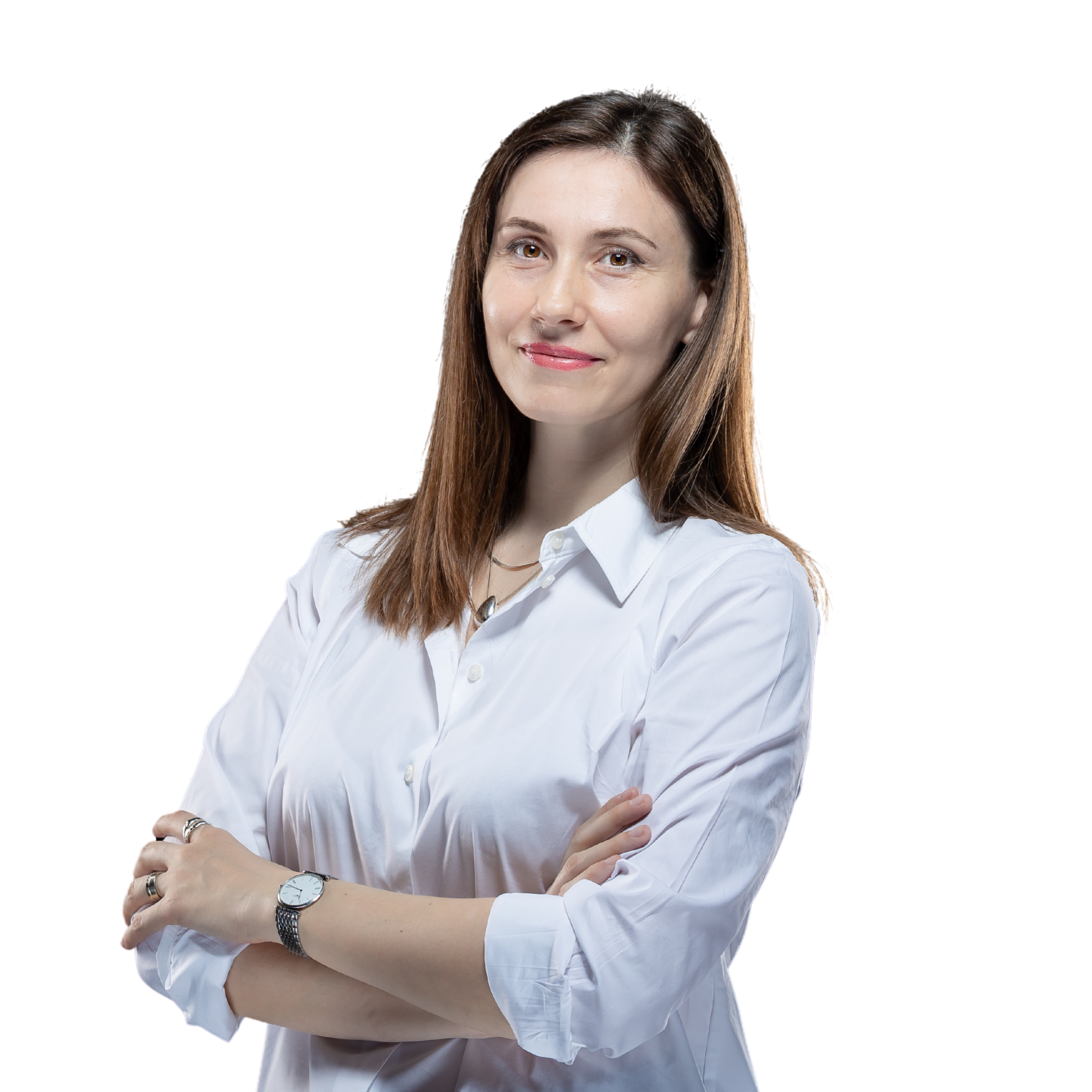 Woman with long brown hair wearing a white button-up shirt, standing with arms crossed and smiling slightly against a plain white background.